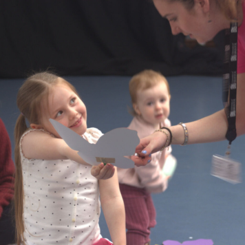 Young person showing butterfly artwork to adult
